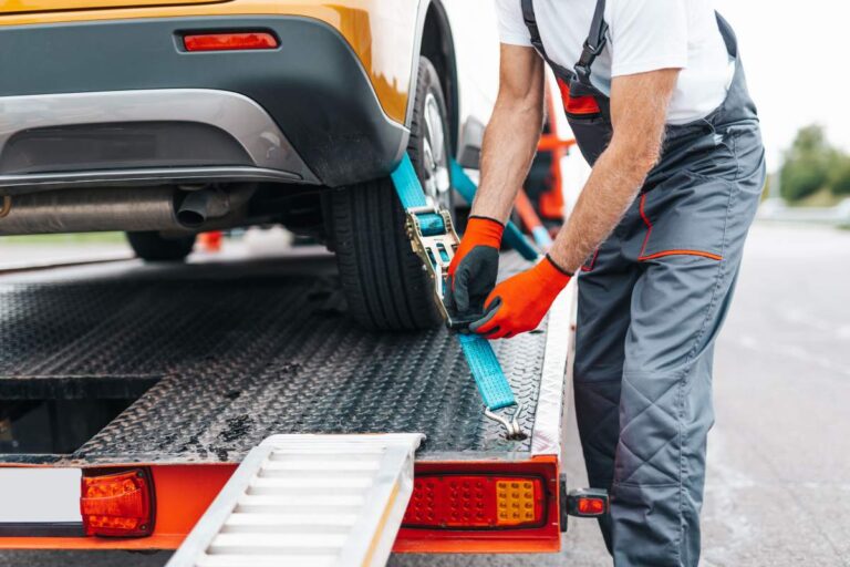 An individual checking tire pressure with a gauge next to a parked car on a residential driveway.