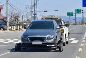 Person standing beside a car with the hood open, checking fluid levels and removing items from the front seat.