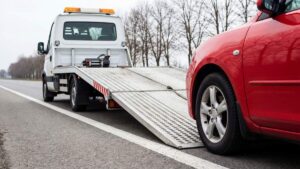 A tow truck operator helps a driver beside a stranded car on a suburban roadside.
